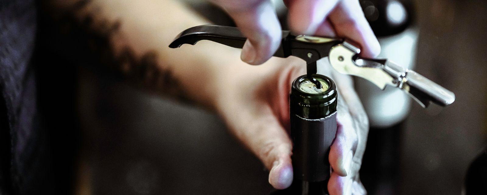 Hand opening a wine bottle with a corkscrew — K&L Wine Merchants accessories for opening, serving, and preserving wine