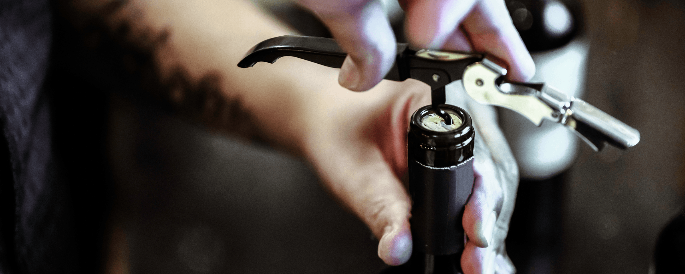 Hand opening a wine bottle with a corkscrew — K&L Wine Merchants accessories for opening, serving, and preserving wine